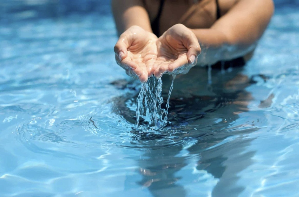 Professional pool cleaning technician cupping crystal clear pool water in San Gabriel