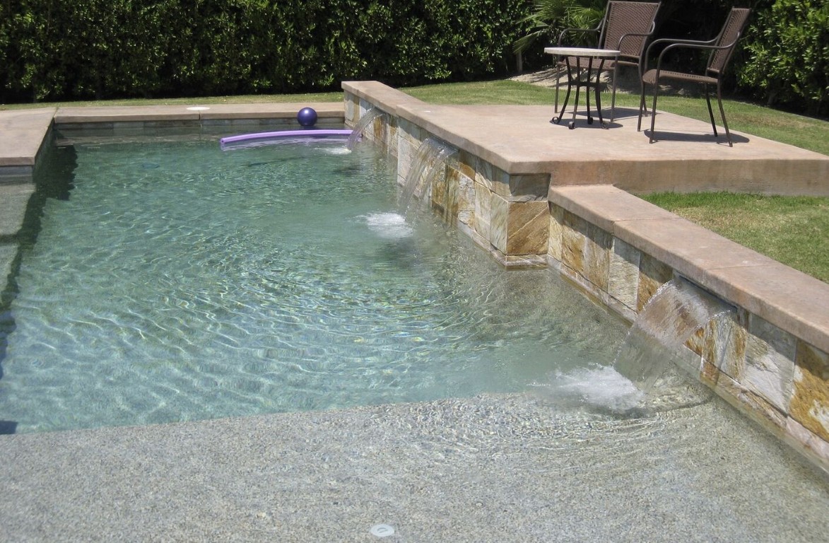 Pool with natural stone waterfall feature and clean tile in San Gabriel